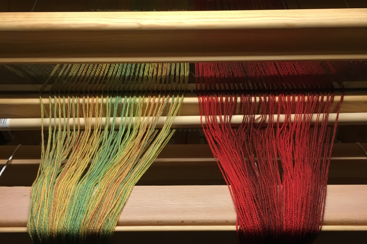 Photo of the front of the loom, showing the reed setup with 4 threads, a small gap, one warp, a gap, the second warp, a gap, and 4 more threads.