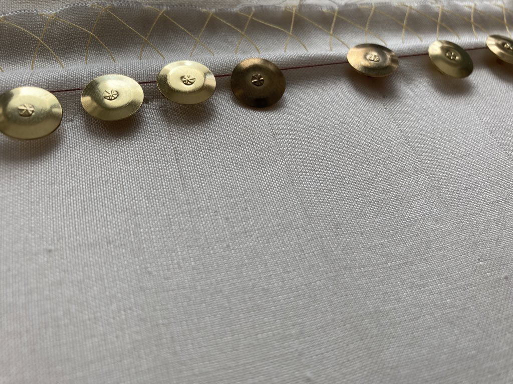Close-up of the thumb tacks, showing long cracks in the silk fabric.