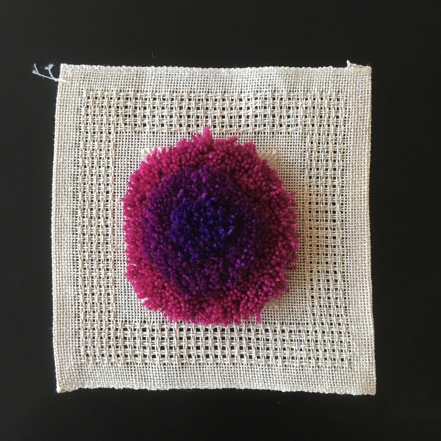 A small piece of fabric with a lace frame and a fluffy center.